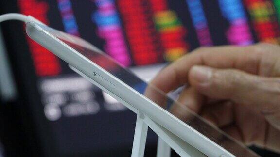 商业女性使用iPad平板电脑进行股票交易与股票交易所市场行情板的背景