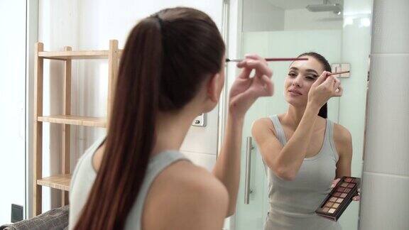 化妆涂眼影和看镜子的女人