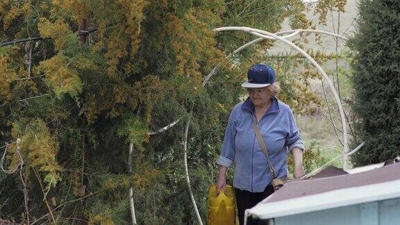 园丁女人拿着水壶走在花园的后院