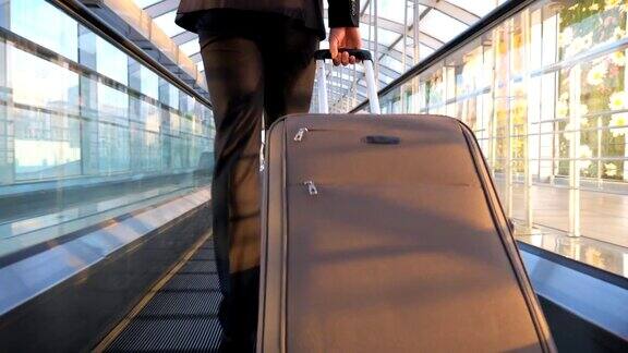 富商的脚和他的行李走在候机楼大厅一个年轻人正带着行李飞往飞机出差后视图慢动作