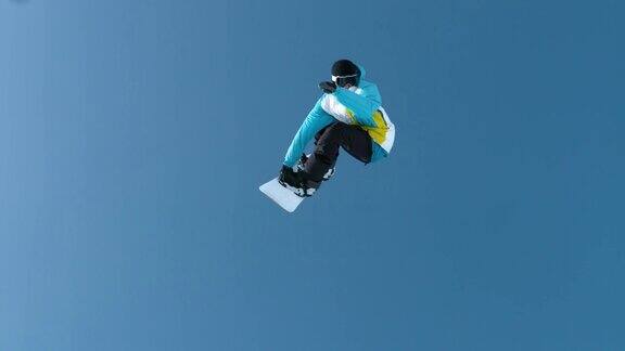 慢动作:年轻的男性滑雪者抓住巨大的空气做一个旋转的把戏