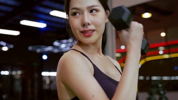 黑色哑铃组年轻的亚洲女子在运动健身馆的架子上举着金属哑铃这是重量训练设备