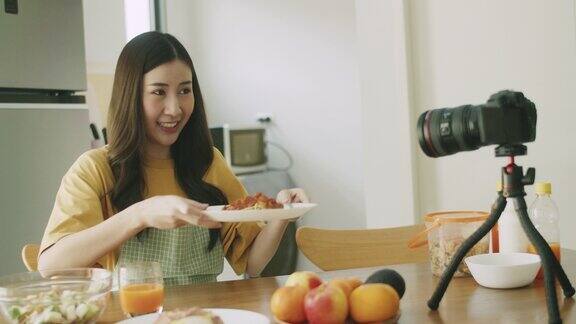 年轻微笑美丽的女性美食博主在家里的厨房拍摄视频教程社交媒体影响者