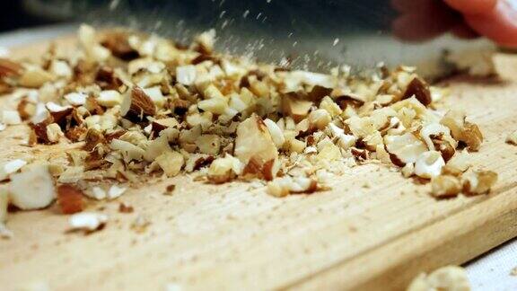 厨师的手在木砧板上切着混合的坚果