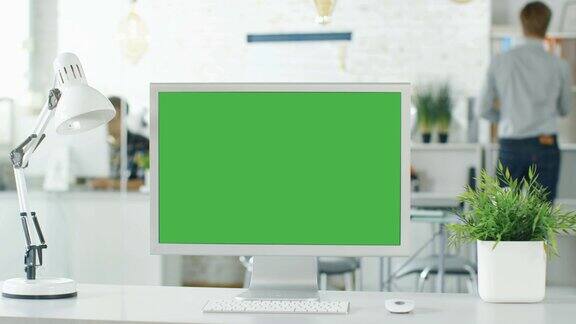 个人电脑绿色萤幕的特写背景模糊和明亮的办公室人们通过办公室例行公事