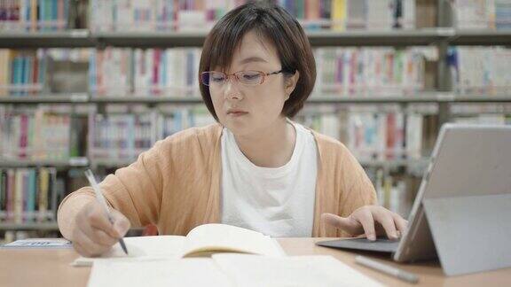 亚洲女人在图书馆用笔记本电脑