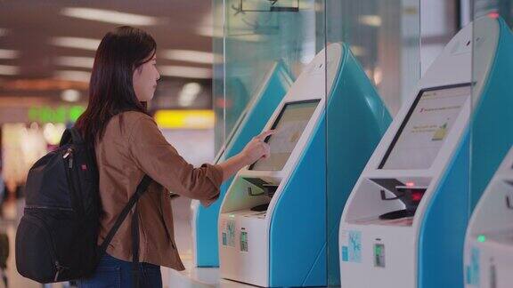 亚洲女旅客在机场使用扫描登机牌机的数字显示和用手机查询数据