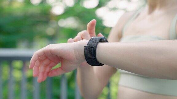 特写一名亚洲女子在慢跑时用智能手表记录时间