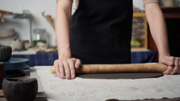 无名年轻女子在陶艺工作室用木头塑造粘土陶艺女孩把粘土压扁到盘子里教育理念、商业、艺术人才和手工创作