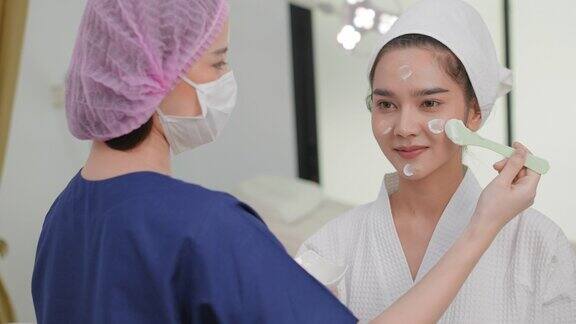 近距离观察年轻美丽的亚洲妇女在浴衣与毛巾头巾应用保湿滋养面霜的手漂亮的亚洲女性每天做美容美容或治疗健康的皮肤