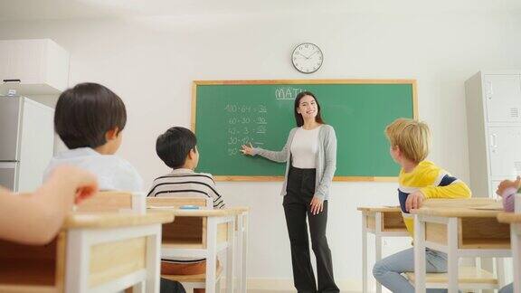 一群小学生在教室里跟着老师学习迷人美丽的女指导老师在幼儿园用快乐有趣的活动为幼儿讲解和教育