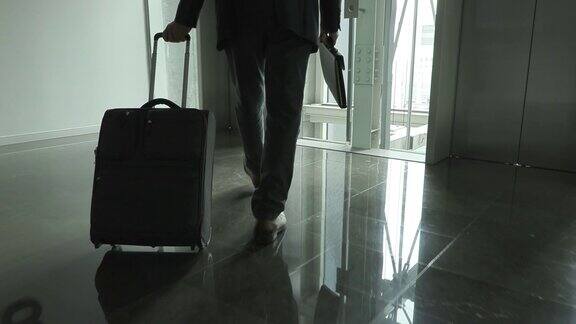 画面中的男人正拿着公文包和手提箱沿着走廊走着慢镜头
