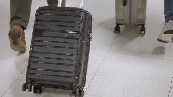 下半部分两个人在机场拖着他们的轮式行李