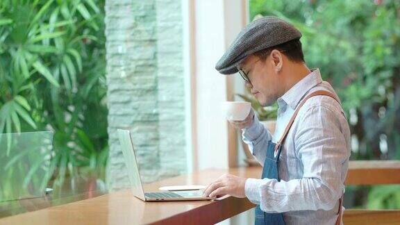 4K亚洲男人咖啡馆老板在笔记本电脑上计算财务账单