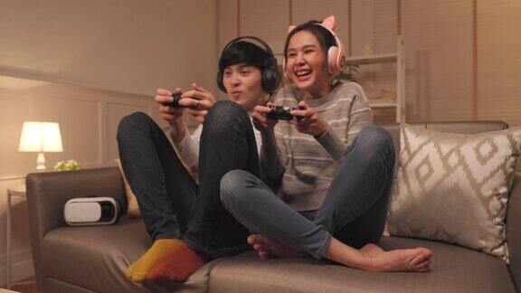 年轻的亚洲夫妇一家人在家里的客厅里用霓虹灯玩在线视频游戏