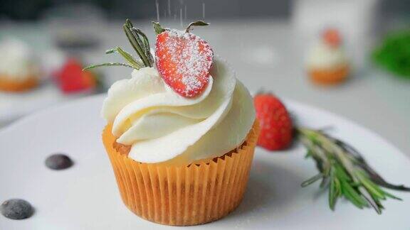 甜点厨师女手装饰美味的纸杯蛋糕白奶油顶部切草莓块在厨房