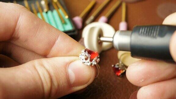 这位珠宝商正忙着把一块宝石镶在金戒指上专业珠宝商用一种特殊的工具打磨金戒指上的红色宝石