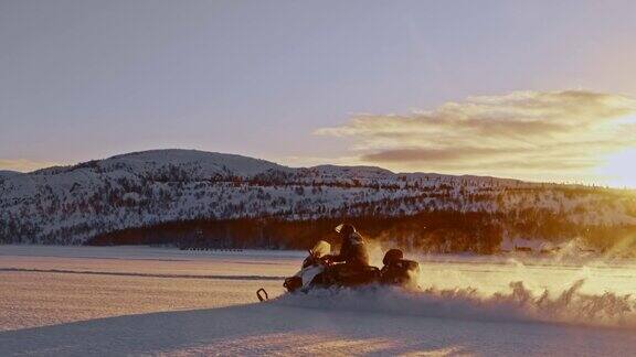 日落时分骑着雪地摩托穿过雪地