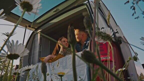 一对相爱的年轻夫妇躺在草地上的露营车上玩得很开心