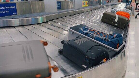 行李袋在传送带上运输在机场航站楼的传送带上人们在高峰时间等候