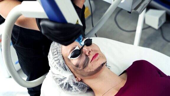 近距离美容师做碳剥离程序激光闪光清洁病人面部皮肤