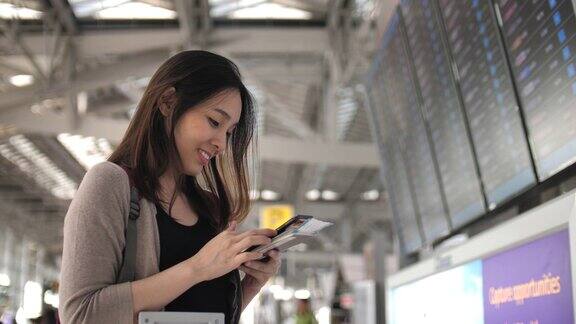 一名亚洲年轻女子在机场玩智能手机