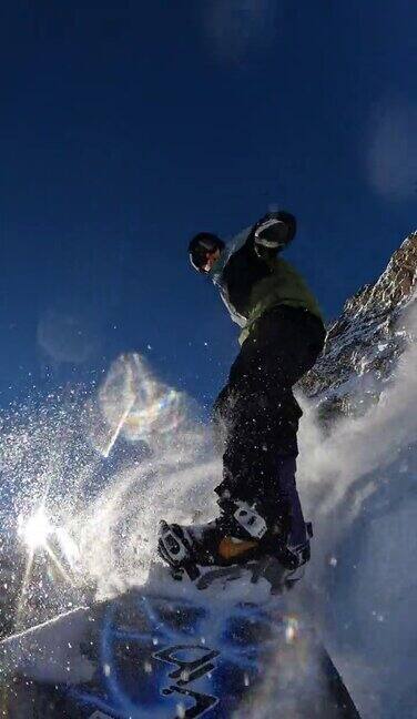 一名自由式滑雪板运动员从积雪覆盖的斜坡上滑下的垂直自拍