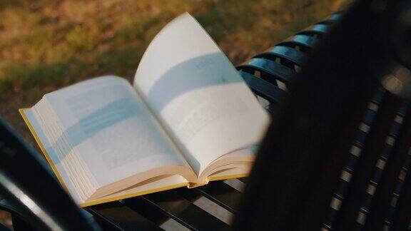 日落时分一本被遗忘的书摊开在公园的空长凳上