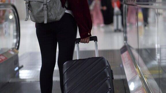 旅行家女士走过机场航站楼与手提箱在机场旅游概念