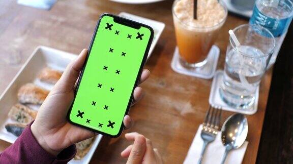 一名女子在餐厅使用绿色屏幕的手机