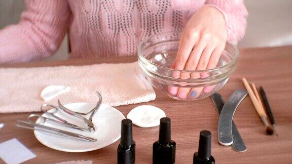 在家里修指甲一个女人把手伸进一碗水里手特写修甲工具放在桌上