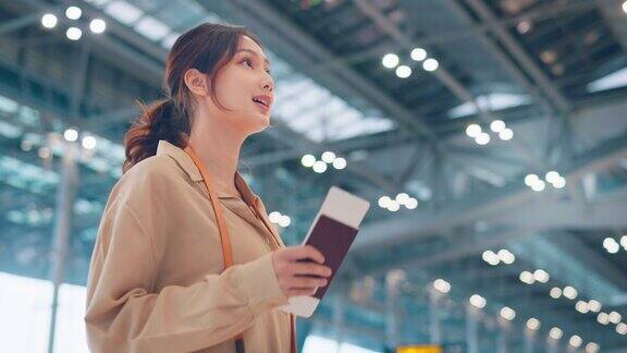 亚洲女性旅客在机场候机楼查看航班时刻表旅游旅行概念