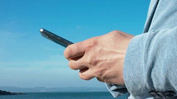 一个穿蓝色夹克的人在海边用手机