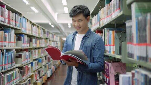 聪明的亚洲人大学学生阅读之间的书架与校园图书馆的copyspace