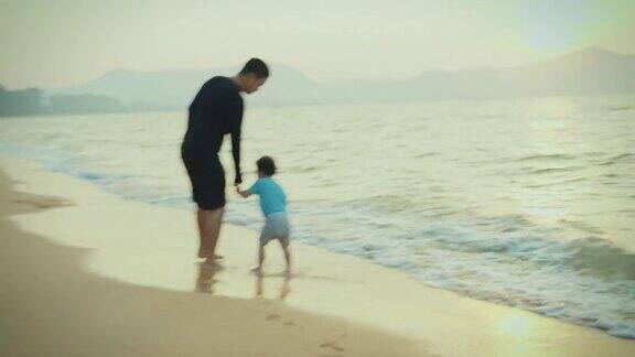 父亲带儿子的家庭旅行假期在海滩上跑步和散步