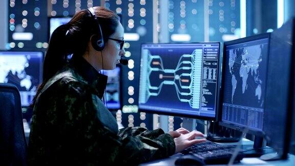 女军事技术支持专业人员给耳机指令她在一间有很多工作屏幕的监控室里