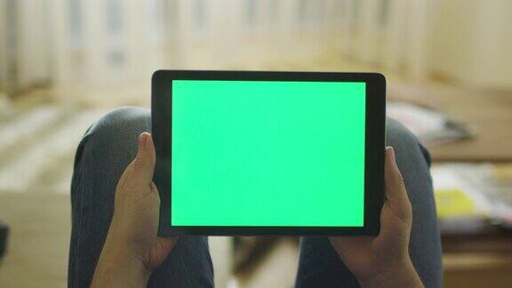 男人躺在家里的沙发上拿着平板电脑绿色屏幕处于横向模式