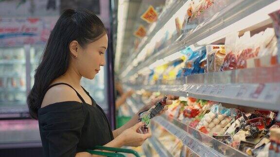 年轻女性在商店里看着商品并阅读标签在超市选购蔬菜、水果和购物的人