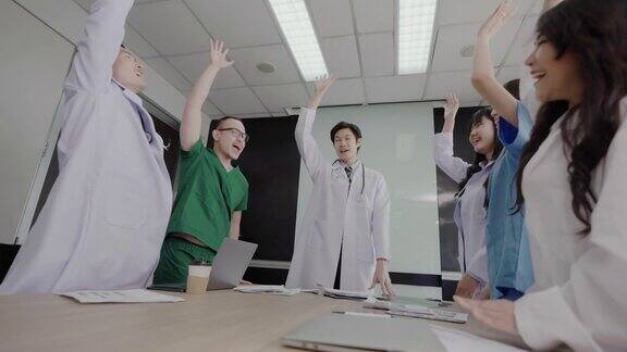 一群亚洲医生双手合十举起头顶