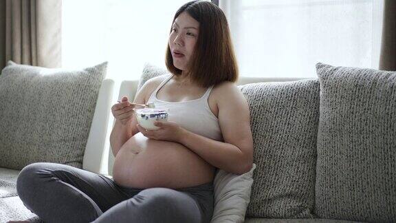 孕妇在家里客厅的沙发上吃健康食品