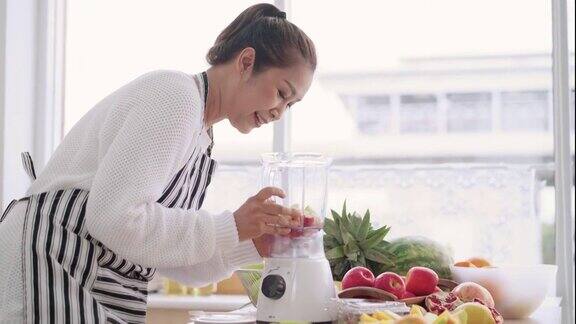 亚洲妇女准备自制水果冰沙与不同的口味草莓石榴橘子和酸奶健康的天然益生菌调味饮料侧视