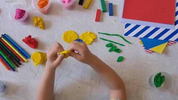 小女孩的手用五颜六色的粘土面团制作花朵橡皮泥用粘土制作家庭教育游戏早期发展教育和娱乐类与孩子