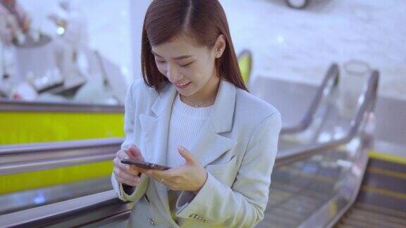 亚洲商业女性步行和使用智能手机在现代办公大楼