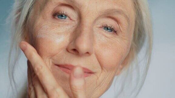 美丽的女性特写肖像轻轻应用下眼霜使用天然抗老化化妆品使老妇人的皮肤柔软光滑无皱纹美容护肤产品