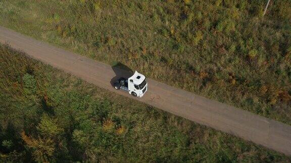 一辆没有拖车的半挂车独自行驶在浓密平坦的森林沥青直空道路上高速公路上的俯视图跟随车辆航拍镜头