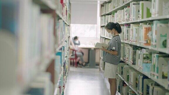 小女孩在图书馆的书架上看书
