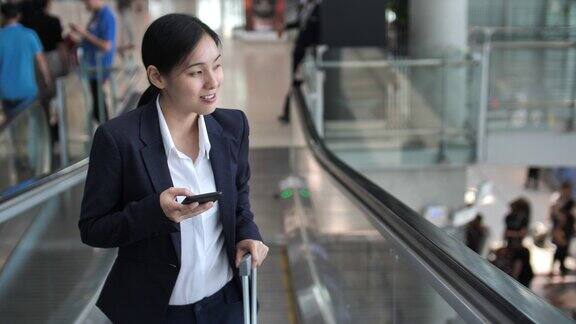 女商人在机场的自动扶梯上使用电话
