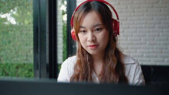 年轻的亚洲女性坐在网吧里一边喝咖啡一边用笔记本电脑听音乐互联网是一切