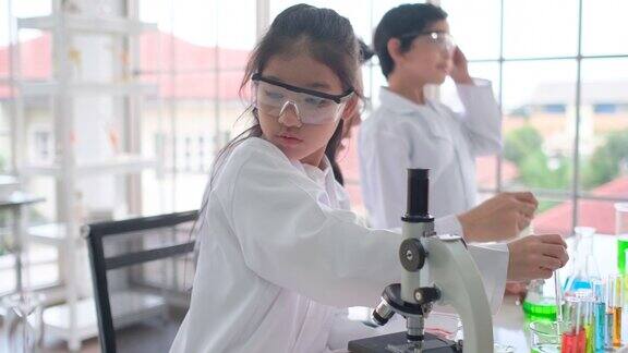 年轻的科学家女孩集中测试颜色化学在教室与她的同学在后台工作