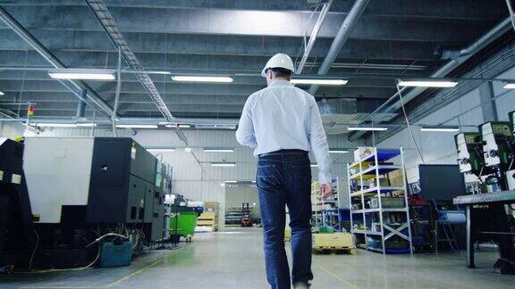 戴安全帽的工程师正在穿过工厂后视图